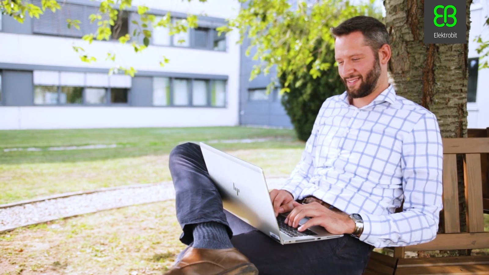 Ein Mitarbeiter während der „Mobile Work“ im Freien auf einer Bank